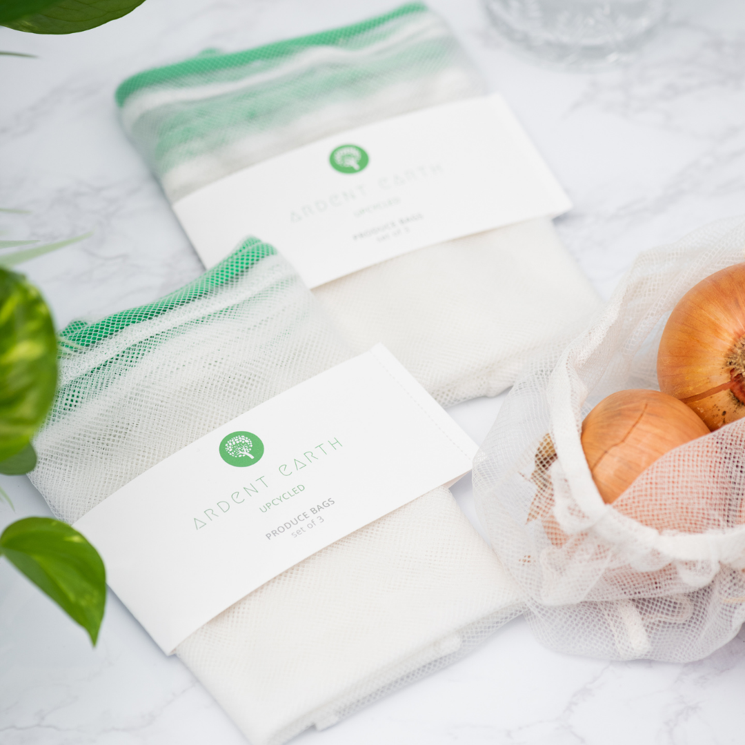 two packages of produce bags sit next to an open produce bag of onions, on a marble surface